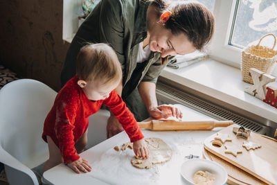 Happy mother and little baby toddler girl making christmas cookies in home kitchen. mother and