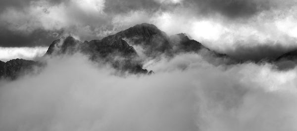 Low angle view of fog covered mountains against sky