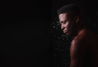 Portrait of young man against black background