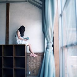 Girl sitting on shelf and reading a book