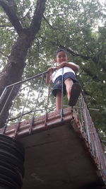 Low angle view of boy standing against trees