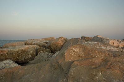 Rocks by sea against clear sky