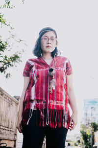 Portrait of young woman standing against sky