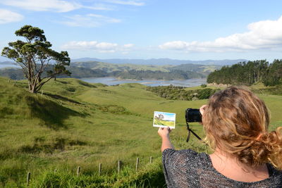 Rear view of woman photographing on landscape