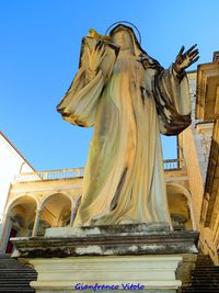 Low angle view of statue against historic building against sky