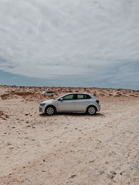 Vintage car on sand against sky