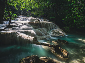 Epic waterfall smooth flowing stream with sunlight in forest. erawan falls, kanchanaburi, thailand.