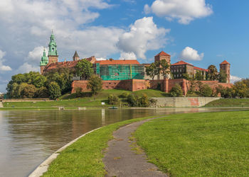 View of buildings by river against cloudy sky