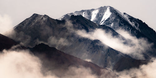 Low angle view of a plane and snowcapped mountains against sky