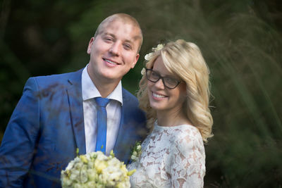 Portrait of smiling bridal couple standing at park