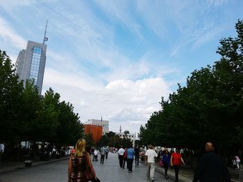 People walking on street in city against sky