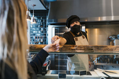 Male restaurant owner giving credit card to female customer