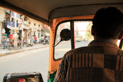 Rear view of man driving rickshaw on street