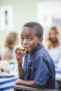 Portrait of smiling boy eating watermelon at party in garden