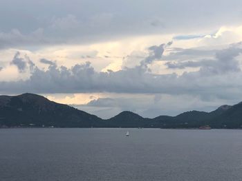 Scenic view of sea by mountains against sky