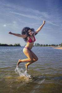 Woman jumping in sea against sky