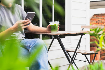 Midsection of woman using mobile phone while sitting on table