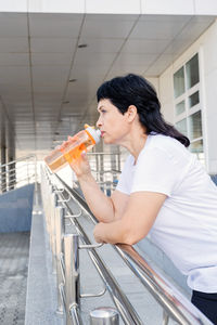 Side view of young woman sitting on railing