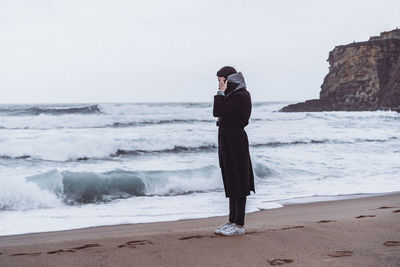 Full length of man standing on beach against sky