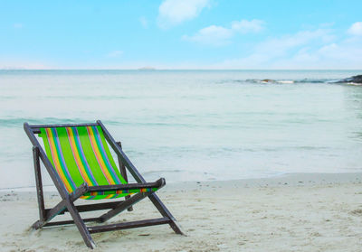 Chairs on beach against sky