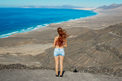 Rear view of woman standing at beach