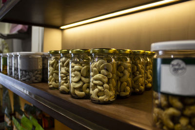 Spicy dry fruit cashew nuts packed in glass bottle arranged in racks in shop