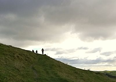 People walking on mountain road against sky