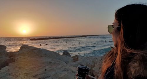 Portrait of woman at beach against sky during sunset