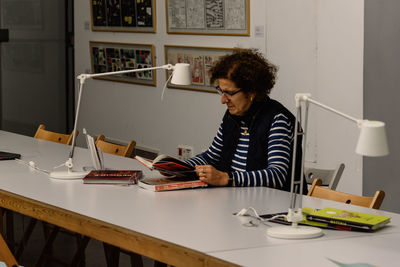 Mature woman reading book on desk