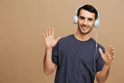 Portrait of young man standing against brown background