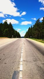 Road by trees against blue sky