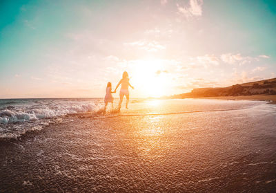 People on beach against sky during sunset