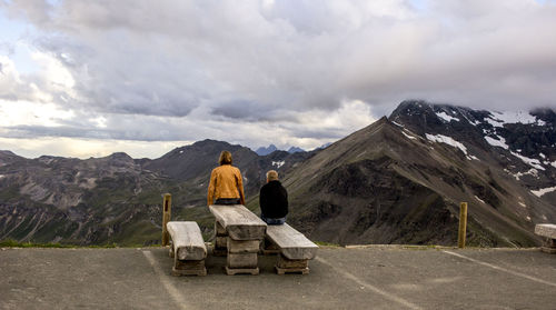 Rear view of man and woman sitting against mountain