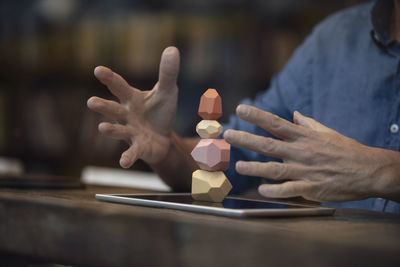 Businessman balancing stack of stones on tablet pc at cafe