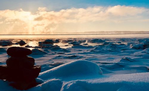 Rear view of frozen sea against sky during winter