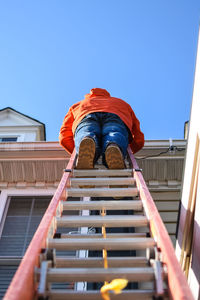 Low angle view of woman standing on ladder by house