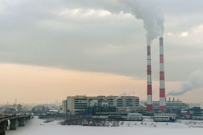 Smoke emitting from factory against sky during winter