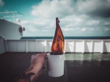 Close-up of hand holding umbrella against sea