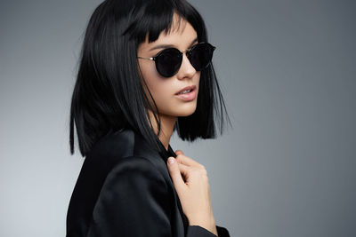 Young woman wearing sunglasses against wall