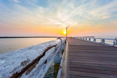 Pier over sea against sky during sunset