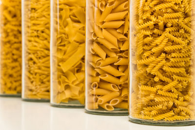 Various noodle sorts filled in high glasses against white background