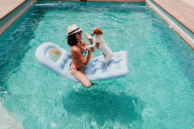 High angle view of woman with dog in swimming pool