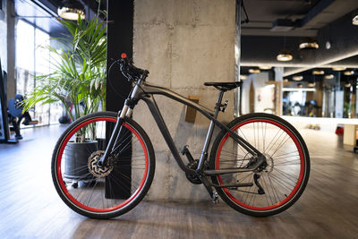 Modern black bicycle parked near concrete pillar inside contemporary illuminated gym during workout