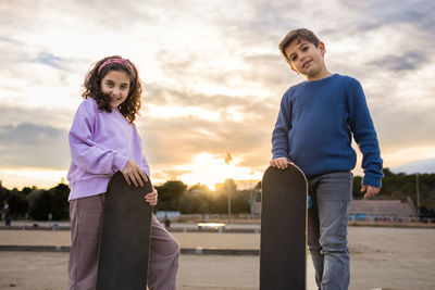 Two kids with a skate board at sunset