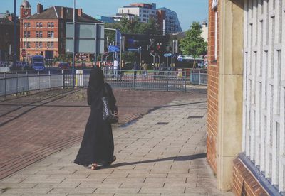 Full length of woman standing on sidewalk in city