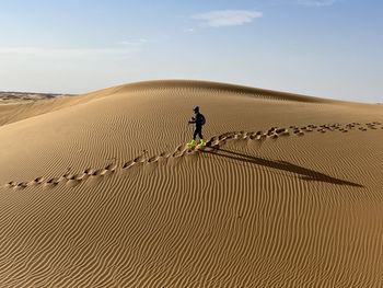 Rear view of man walking on sand at beach against sky