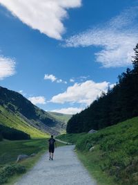 Rear view of man walking on road against sky