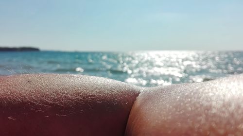 Midsection of woman on beach against sky