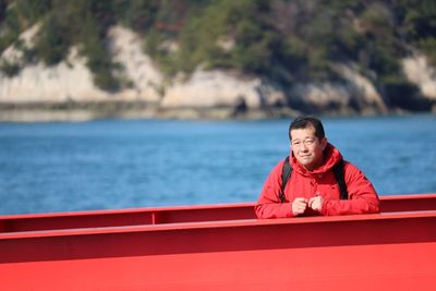 Portrait of man on red boat against sea