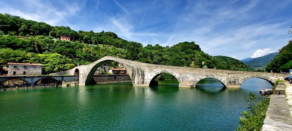 Arch bridge over river against sky